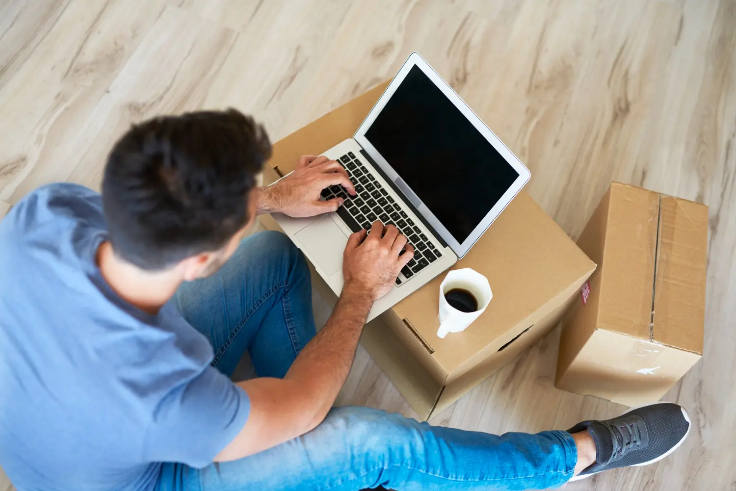 Close up of man using a laptop next to moving boxes for it office relocation services