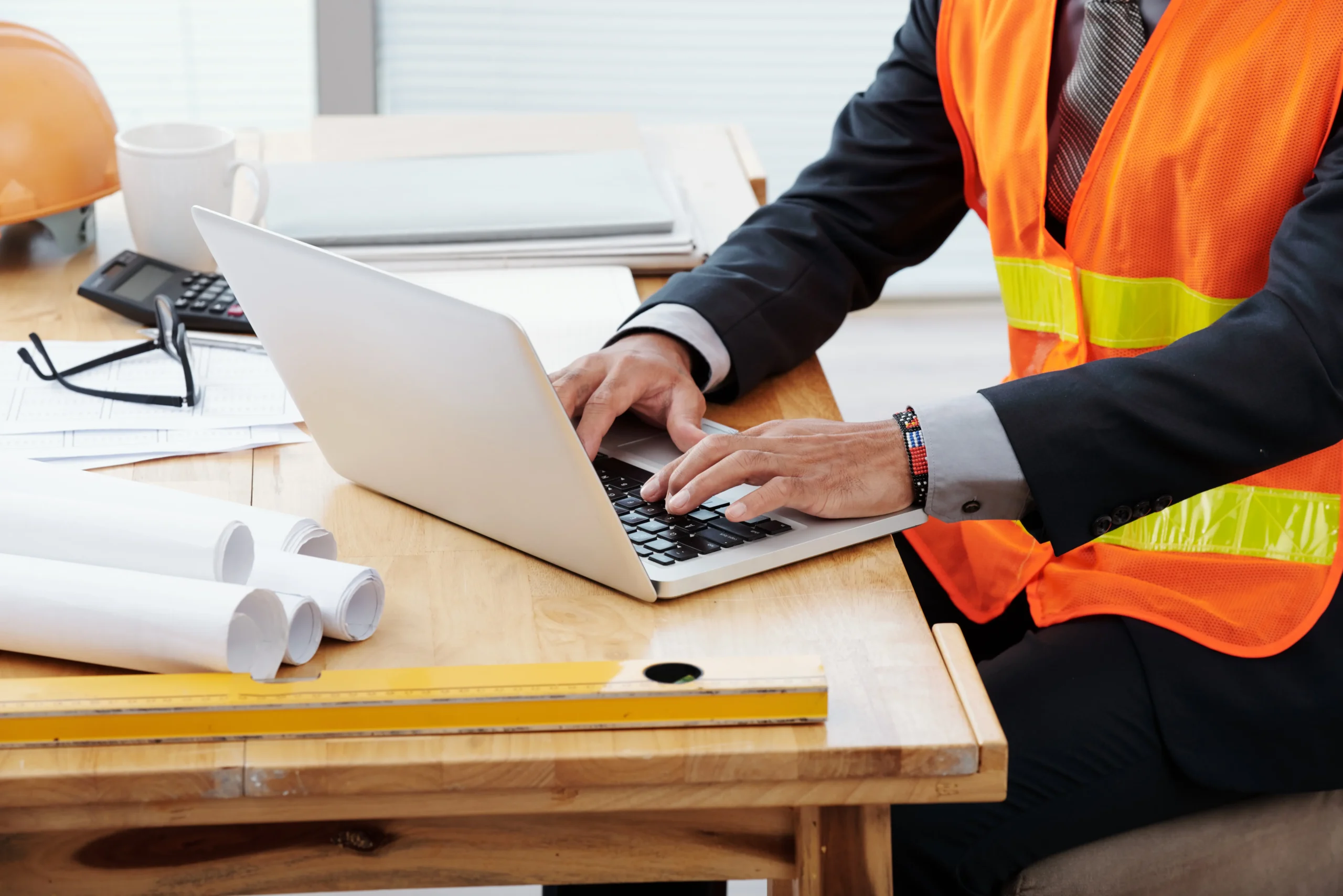 A man wearing neon safety vest working on desk using laptop for IT Solutions in Construction in Seattle