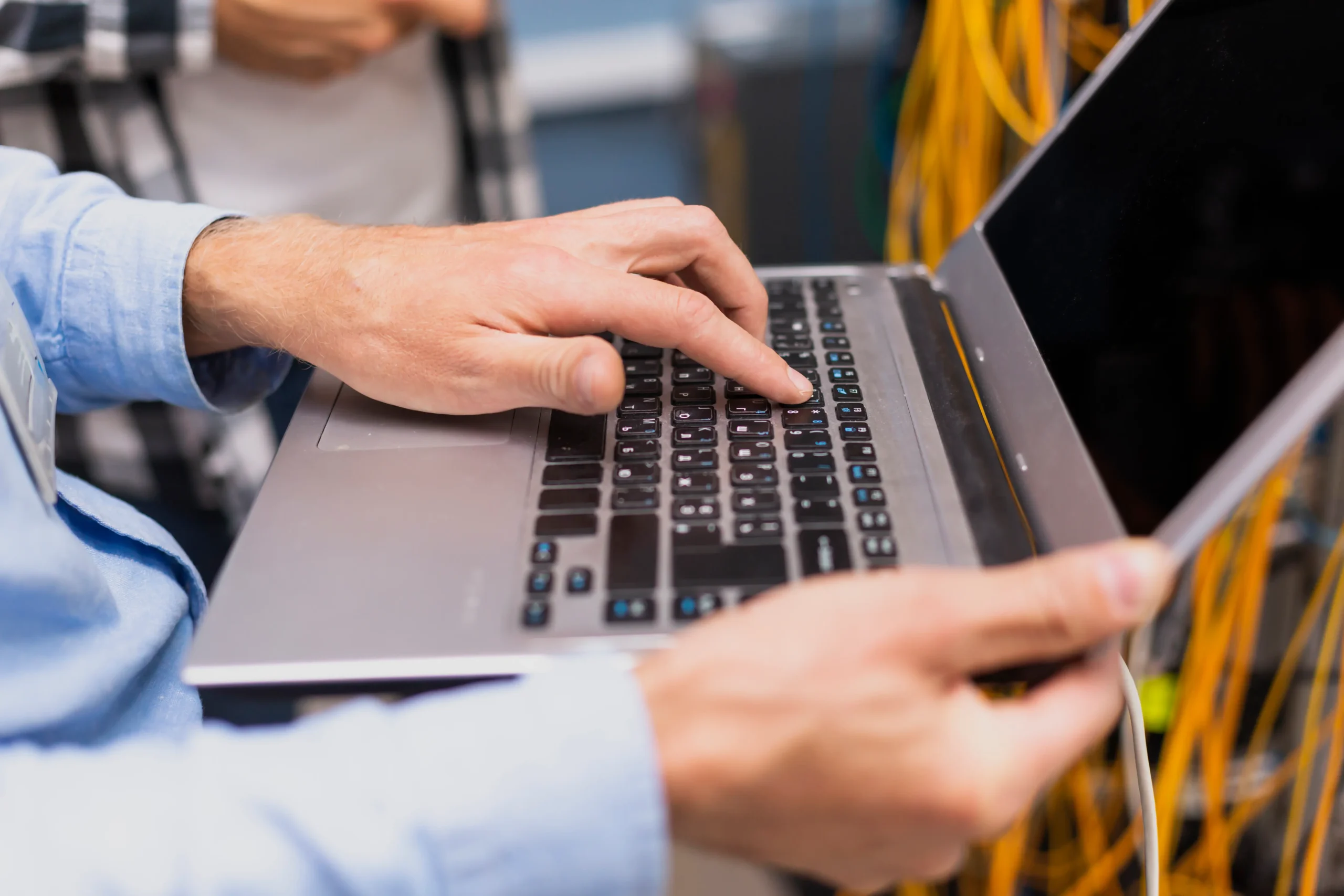 A certified CompTIA Network holding a laptop in a server room